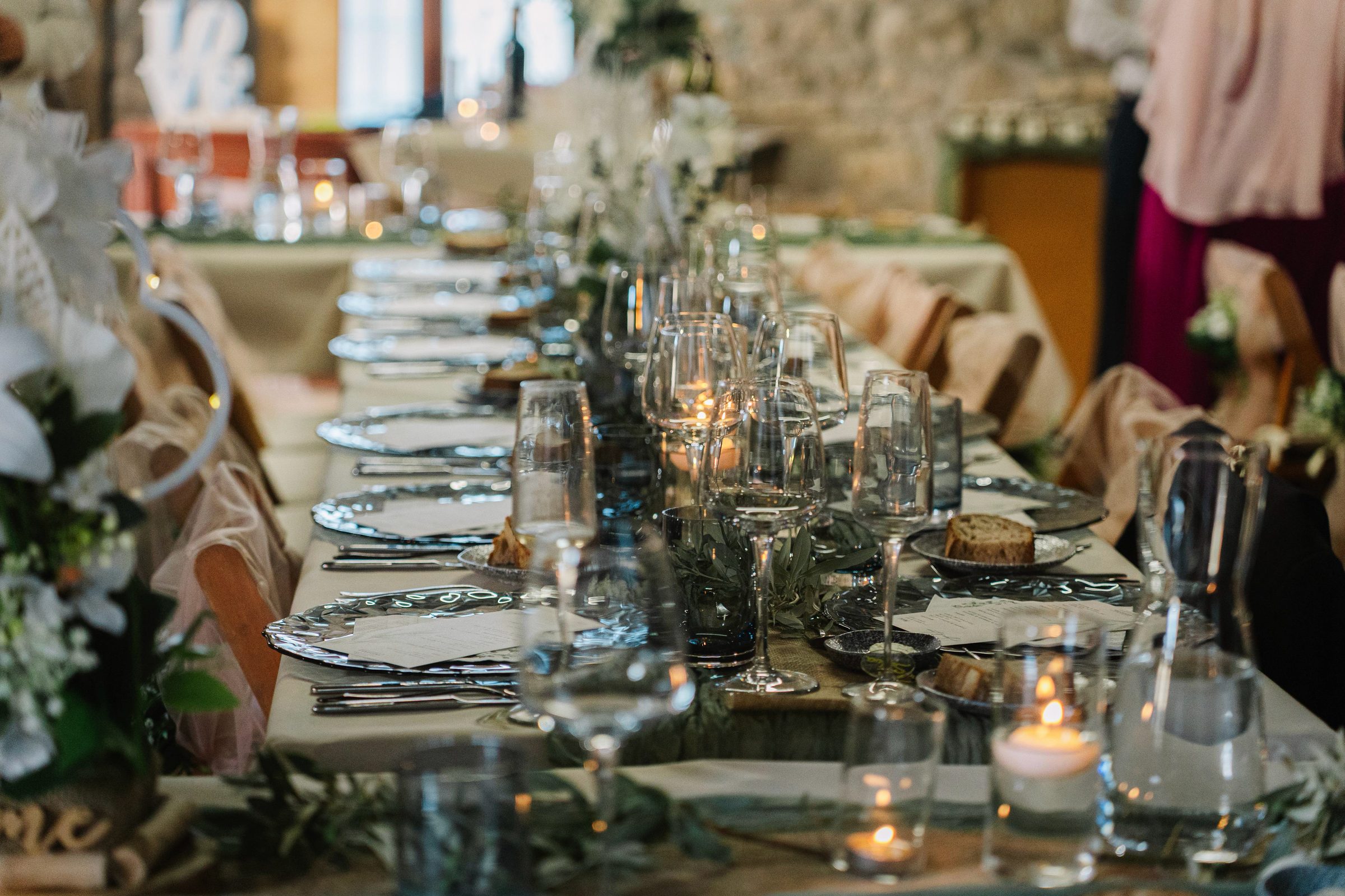 Taula de banquet parada per a una celebració, amb espelmes i branques d'olivera